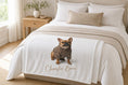 Load image into Gallery viewer, Charlie Bear plush blanket folded at the foot of a bed.
